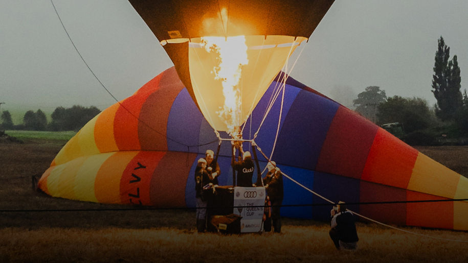 Several people around a hot air balloon using the burner to inflate the balloon